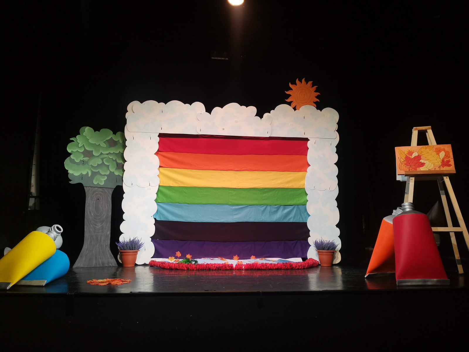 Le décor monté sur un plateau de théâtre, éclairé de face, l’arbre en carton d’un côté et le chevalet de l’autre.